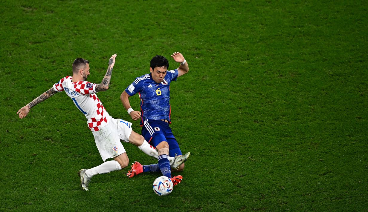Pemain Timnas Jepang, Wataru Endo (kanan) berebut bola dengan pemain Timnas Kroasia, Brozovic pada laga 16 besar Piala Dunia 2022 di Al-Janoub Stadium, Al-Wakrah, Qatar, 5 Desember 2022. (AFP/Anne-Christine Poujoulat)