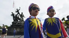 Dua anak laki-laki yang mengenakan kostum bendera nasional Malaysia berfoto di depan Monumen Nasional saat perayaan Hari Nasional ke-64 untuk memperingati kemerdekaan dari penjajahan Inggris di Kuala Lumpur, Malaysia, Selasa (31/8/2021). (AP Photo/Vincent Thian)