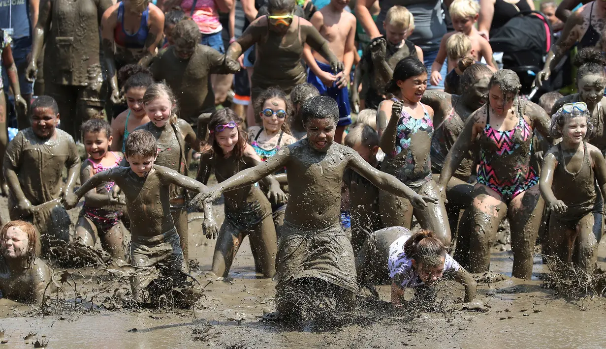 Ratusan anak berlari ke dalam kubangan berisi lumpur saat perayaan Mud Day atau Hari Lumpur Tahunan di Westland, Michigan, AS, Selasa (10/7). Dalam Mud Day kali ini para pesertanya yang ikut adalah anak-anak.  (AP/Carlos Osorio)