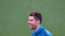 Penyerang Real Madrid, Cristiano Ronaldo tertawa saat mengikuti sesi latihan di Madrid, Spanyol (10/4). Real Madrid akan bertanding melawan Juventus pada leg kedua perempat final Liga Champions. (AP Photo/Paul White)