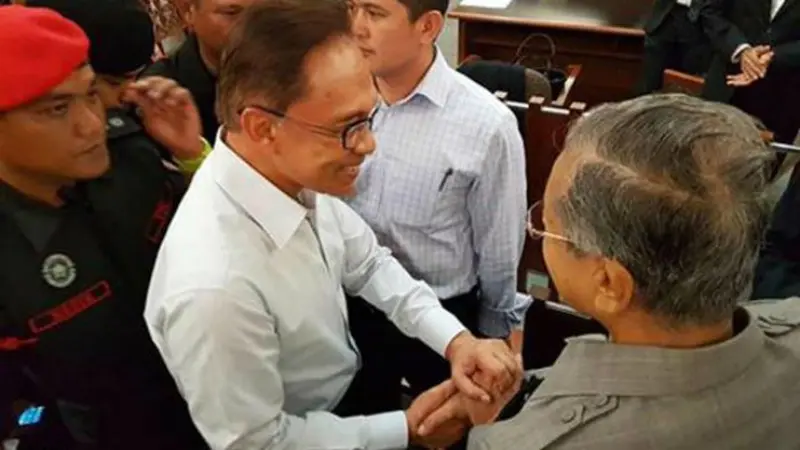 Anwar Ibrahim (kiri) dan Mahathir Mohamad tampak berjabat tangan di Pengadilan Tinggi Kuala Lumpur