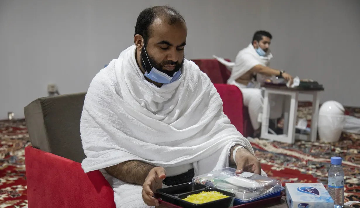 Jemaah makan dalam kamp saat melaksanakan rangkaian ibadah haji di Kota Suci Makkah, Arab Saudi, Kamis (30/7/2020). Hanya sekitar seribu jemaah yang diizinkan untuk melakukan ibadah haji tahun ini karena pandemi COVID-19. (Saudi Ministry of Media via AP)