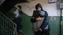 Penduduk setempat membawa barang-barang mereka dari sebuah bangunan tempat tinggal yang rusak menyusul serangan rudal Rusia di Kyiv, Ukraina, Senin 15 Juni 2026, di tengah invasi Rusia. (OLEKSII FILIPPOV/AFP)