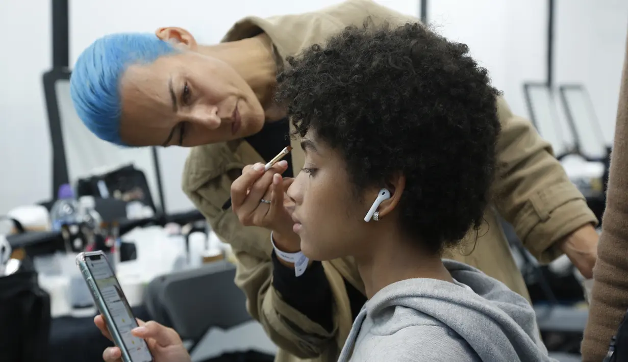Model saat dirias di belakang panggung sebelum memamerkan koleksi busana wanita Fall Winter 2020 Jil Sander selama Fashion Week di Milan, Italia, Rabu, (19/2/2020). (AP Photo/Domenico Stinellis)