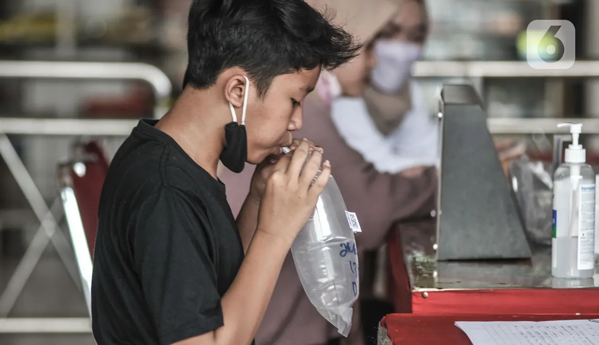 Pemudik meniup kantong saat dites dengan GeNose C19 di Terminal Kampung Rambutan, Jakarta, Minggu (23/5/2021). Pengelola Terminal Kampung Rambutan memberlakukan tes Genose sebagai syarat wajib bagi para pemudik yang baru tiba guna memutus penyebaran virus Covid-19. (merdeka.com/Iqbal S Nugroho)