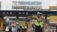 Polisi dan petugas Dishub berjaga di depan Gerbang Tol Bekasi Barat 1, Bekasi, Jabar, Senin (12/3). Ganjil genap ini merupakan kebijakan untuk mengurai kemacetan parah di tol Cikampek-Jakarta, khususnya ruas Bekasi-Jakarta. (Liputan6.com/Arya Manggala)