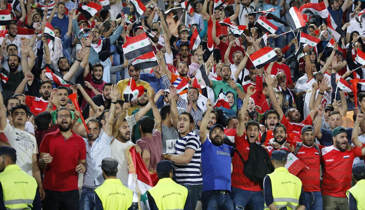 Suporter Suriah berpesta usai menahan imbang Iran 2-2 pada laga kualifikasi Piala Dunia 2018 di Stadion Azadi, Taheran, Selasa (5/9/2017). Finis urutan tiga grup A, Suriah lolos ke babak playoff untuk menantang Australia. (AFP/Atta Kenare)