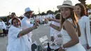 Peserta dalam balutan serba putih  bersulang sampanye saat Dinner en Blanc atau "makan malam putih" di Tuileries Gardens, Paris, Kamis (6/6/2019). Peserta acara ini harus diundang oleh mereka yang sudah terdaftar di situsnya atau mengenal salah satu penyelenggara Diner en Blanc (Lucas BARIOULET/AFP)