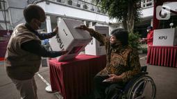 Penyandang disabilitas memasukkan surat suara saat simulasi Pemilu 2024 di Kantor KPU RI, Jakarta, Selasa (22/3/2022). Simulasi digelar untuk memberikan edukasi kepada masyarakat terkait proses pemungutan dan penghitungan suara pemilu serentak tahun 2024. (Liputan6.com/Faizal Fanani)