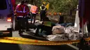 Petugas menutupi jasad penumpang yang tewas akibat bus wisata yang mereka tumpangi terbalik di ruas jalan dekat Taipe, ibu kota Taiwan, Selasa (14/2). Hingga saat ini kepolisian setempat masih melakukan investigasi terhadap kecelakaan tersebut. (AP Photo)