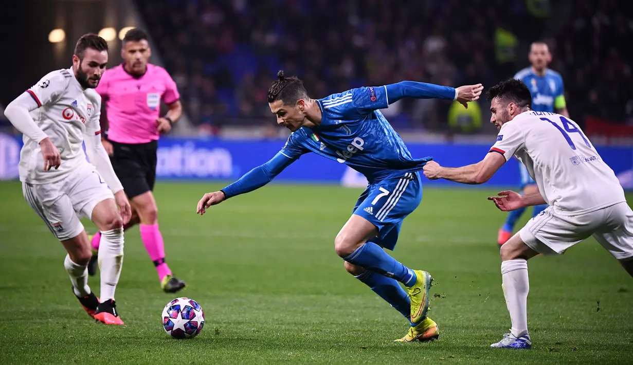 Pemain Juventus Cristiano Ronaldo (tengah) berebut bola dengan pemain Lyon Leo Dubois (kanan) dan Lucas Tousart (kiri) pada leg pertama babak 16 besar Liga Champions di Stadion Parc Olympique Lyonnais, Decines-Charpieu, Perancis, Rabu (26/2/2020). Lyon menang 1-0. (FRANCK FIFE/AFP)