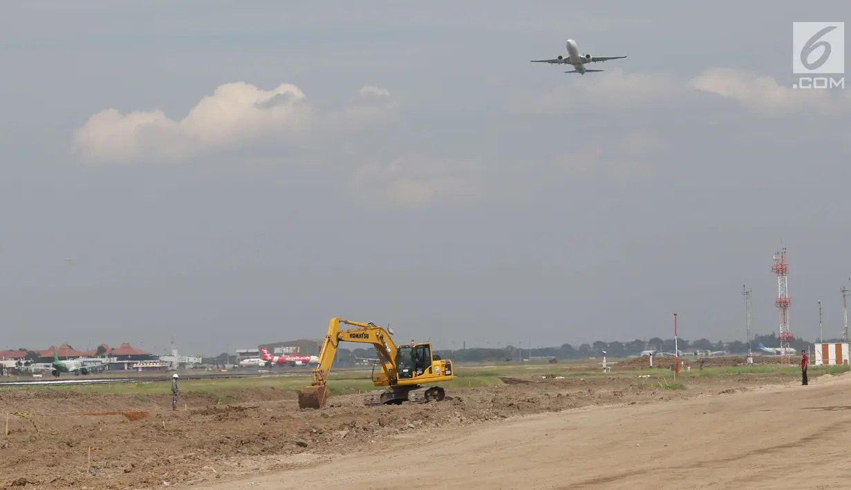 Pesawat melintas di atas proyek pembangunan runway dan taxiway 3 di Bandara Soekarno-Hatta, Tangerang, Kamis (21/6). Pembangunan taxiway dan runway ketiga dapat membantu mengurai lalu lintas udara yang kian padat di Soetta. (Liputan6.com/Angga Yuniar)