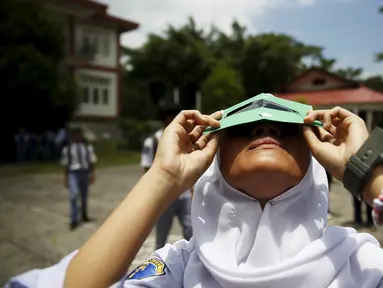 Siswi mencoba melihat matahari dengan kacamata filter buatan sendiri saat workshop bersama Hong Kong Astronomical Society dan LAPAN di sekolah di Ternate, (7/3). Kacamata ini akan digunakan untuk mengamati Gerhana Matahari Total. (REUTERS/Beawiharta)