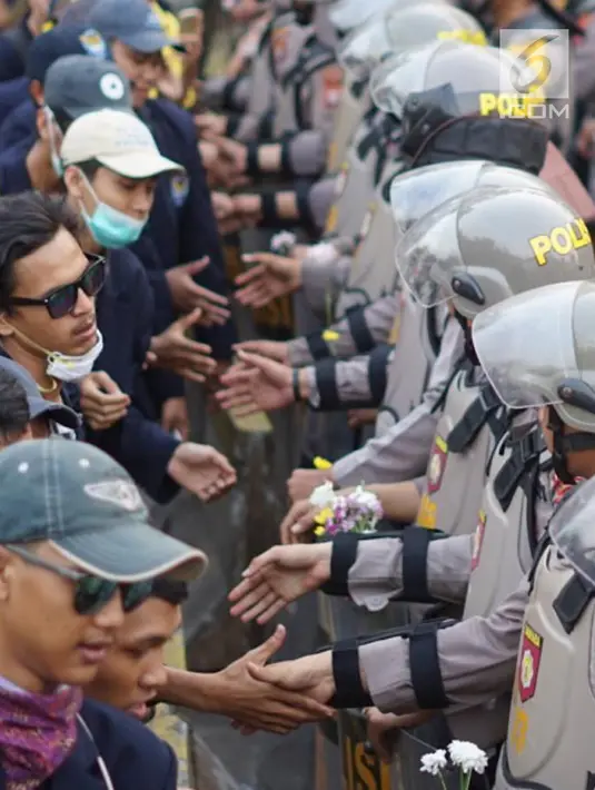 Massa dari Badan Eksekutif Mahasiswa Seluruh Indonesia (BEM SI) bersalaman dengan polisi saat aksi unjuk rasa di sekitar DPR RI, Jakarta, Selasa (1/10/2019). Aksi damai itu berakhir dengan mahasiswa yang bersalaman dan membagikan bunga kepada para polisi yang berjaga (Liputan6.com/Immanuel Antonius)