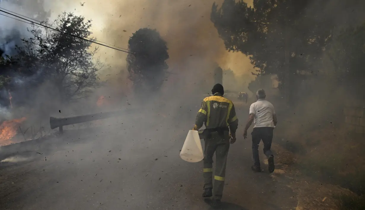 Petugas pemadam kebakaran dibantu personel militer terus berjuang mengendalikan kobaran api di wilayah barat laut dan barat negara tersebut. (MIGUEL RIOPA/AFP)