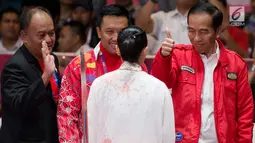 Presiden Joko Widodo mengacungkan jempol memberi semangat atlet wushu Indonesia, Lindswell Kwok saat bertanding di Asian Games 2018, Jakarta, Senin (20/8). Lindswell menyumbang emas kedua untuk Indonesia. (Bola.com/Vitalis Yogi Trisna)