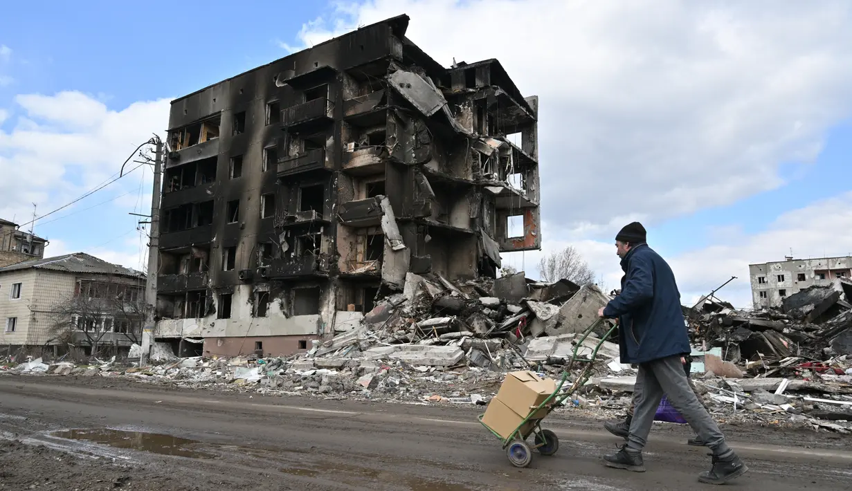 Seorang pria berjalan melewati bangunan yang hancur di kota Borodianka, barat laut Kiev pada 4 April 2022. Saat pasukan Rusia mundur, kota kecil Borodianka, 50 km barat laut Kiev, menjadi reruntuhan. (Sergei SUPINSKY / AFP)
