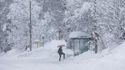 Seseorang mendekati halte bus di jalan yang tertutup salju di Kocevje, dekat Ljubljana Slovenia, Senin (23/1/2023). Badai salju dengan angin kencang telah menghambat lalu lintas di jalan raya utama di Slovenia pada hari Senin dan menyebabkan beberapa bagian negara tanpa listrik untuk sementara waktu. (AP Photo)