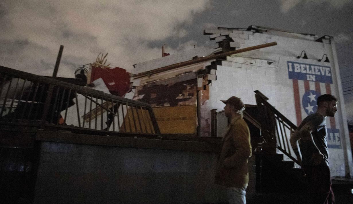 Orang-orang berdiri di luar venue musik Basement East di East Nashville setelah dihantam oleh angin topan, Selasa (3/3/2020). Tornado dekat pusat kota dilaporkan bergerak ke Hermitage, sekitar 16 kilometer timur kota. (Courtney Pedroza / The Tennessean via AP)