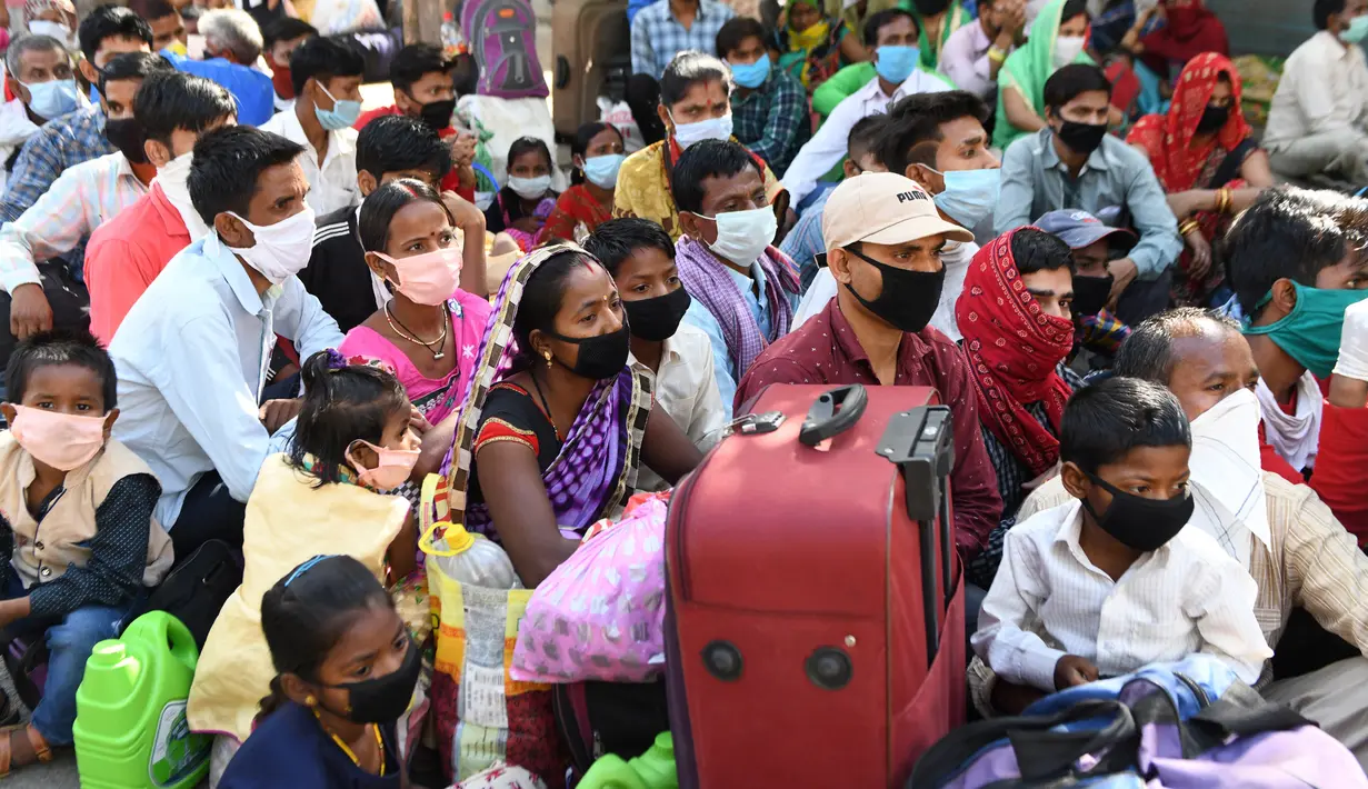 Pekerja migran yang terdampar dan keluarga mereka berkumpul menunggu pemeriksaan medis sebelum pergi dengan kereta api untuk kembali ke kota asal mereka ke Jaunpur, negara bagian Uttar Pradesh, setelah pemerintah melonggarkan lockdown di Amritsar, India, Selasa (19/5/2020). (NARINDER NANU/AFP)