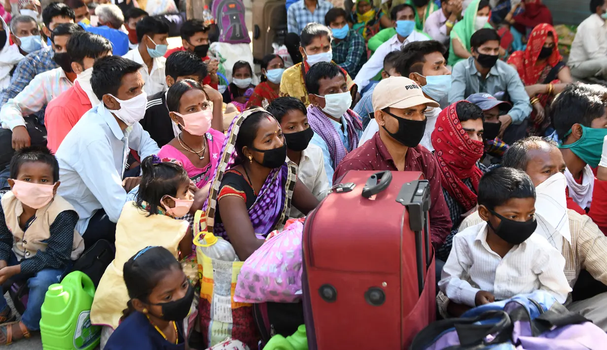 Pekerja migran yang terdampar dan keluarga mereka berkumpul menunggu pemeriksaan medis sebelum pergi dengan kereta api untuk kembali ke kota asal mereka ke Jaunpur, negara bagian Uttar Pradesh, setelah pemerintah melonggarkan lockdown di Amritsar, India, Selasa (19/5/2020). (NARINDER NANU/AFP)