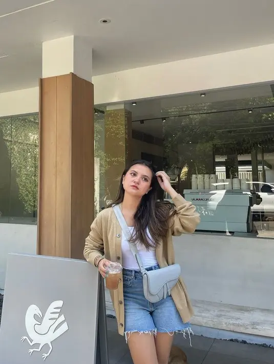 Celana pendek denim ripped juga cocok dipadukan atasan cardigan coklat dengan outer putih spaghetti strap. Sambil mengenakan sling bag dari Dior. [@aruanmarsha]