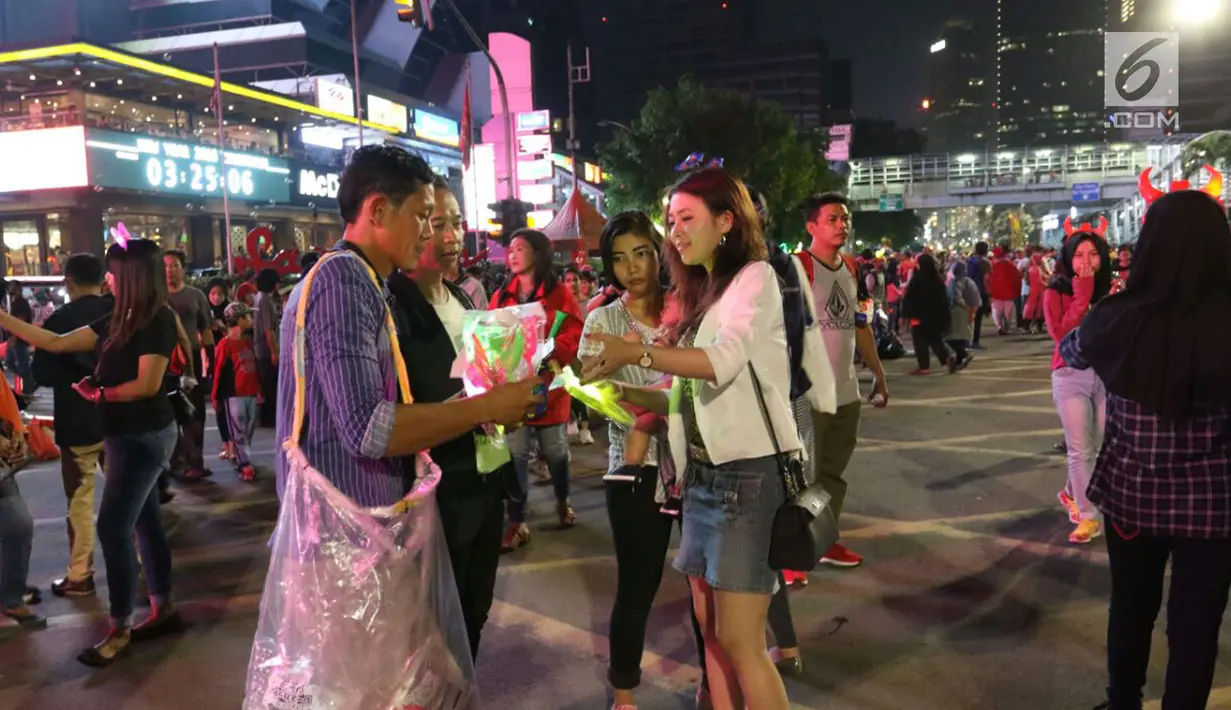 Warga membeli lampu hias kepala pada malam pergantian tahun di MH Thamrin, Jakarta, Minggu (31/12). Pemprov DKI Jakarta memberlakukan car free night mulai pukul 19.00–24.00 WIB.  (Liputan6.com/Angga Yuniar)