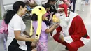 Seorang pria berpakaian seperti Sinterklas memberikan hadiah kepada seorang gadis di ruang gawat darurat sebuah rumah sakit di lingkungan El Cementerio di Caracas, Venezuela pada 25 Desember 2023. (Pedro Rances Mattey / AFP)