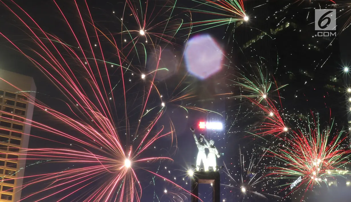 Kembang api menghiasi malam pergantian tahun baru 2019 di kawasan Bundaran HI, Jakarta, Selasa (1/1). Hujan yang mengguyur Jakarta tidak menyurutkan warga menikmati kembang api tahun baru. (Liputan6.com/Angga Yuniar)
