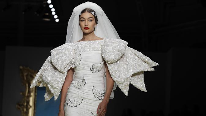 Model Gigi Hadid memakai koleksi Moschino Spring-Summer 2020 selama pekan mode di Milan, Italia (19/9/2019). Gigi tampil anggun dengan sentuhan apik pada balutan gaun pengantin berwarna putih untuk showcase unik yang terinspirasi oleh Alice In Wonderland. (AP Photo/Luca Bruno)