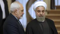 Hassan Rouhani (kanan) mendengarkan Menlu Iran, Mohammad Javad Zarif, sebelum pertemuan di Teheran, Iran (Vahid Salemi / AP)