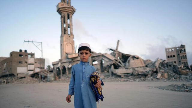 Seorang anak laki-laki Palestina, membawa sajadah, berfoto sebelum mengikuti salat Idul Adha di Khan Yunis, Gaza selatan. (Bashar Taleb/AFP)