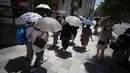 Orang-orang berjalan di trotoar di bawah terik matahari di Tokyo, Selasa (28/6/2022). Pejabat cuaca juga mengumumkan akhir paling awal musim hujan dalam beberapa dekade. (AP Photo/Eugene Hoshiko)