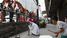 Anggota kelompok barongsai melihat aksi anak-anak melakukan tarian singa di distrik Chinatown, Manila (4/2). Anak-anak jalanan ini tampil lucu dengan alat seadanya seperti ember dan kerdus untuk menyambut Tahun Baru Imlek. (AFP Photo/Ted Aljibe)