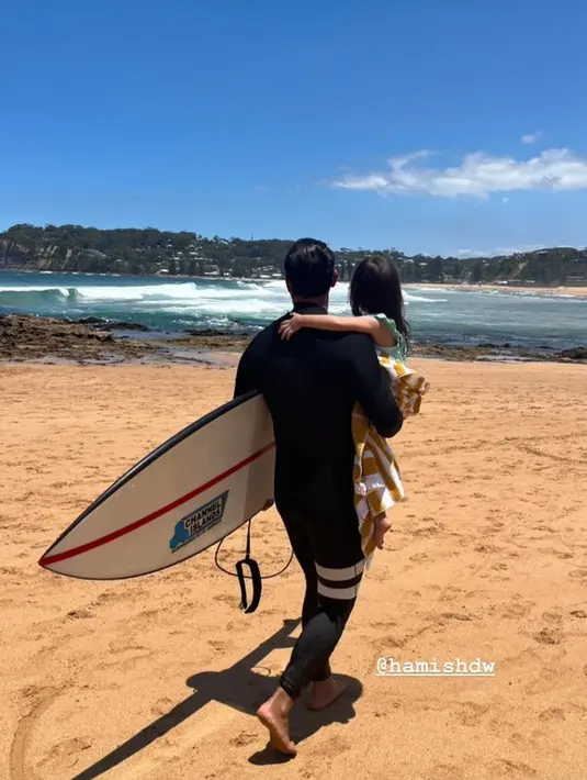 Zalina juga tampak bahagia digendong sang ayah yang bersiap dengan papan surfing-nya. [Instagram @raisa6690]