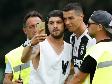 Seorang suporter Juventus berselfie dengan Cristiano Ronaldo selama pertandingan persahabatan antara Juventus A dan tim B, di Villar Perosa, Italia utara, (12/8). Suporter tersebut masuk ke lapangan pada babak pertama. (AP Photo/Antonio Calanni)
