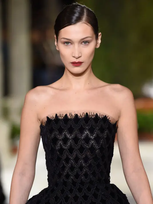 Model Bella Hadid berjalan di atas catwalk mengenakan koleksi terbaru dari Oscar de la Renta dalam New York Fashion Week, AS (12/2). Bella Hadid tampil cantik dengan gaun hitam panjang tanpa lengan. (AFP Photo/Slaven Vlasic)