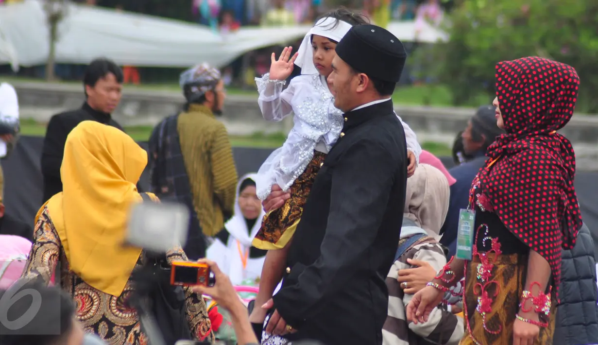 Seorang anak berambut gimbal digendong saat akan melakukan ruwatan atau pemotongan rambut gimbal di komplek candi Arjuna, Dieng, Jateng, Minggu (3/7). Acara ini dilaksanakan pada 5-7 Agustus 2016. (Gholib)
