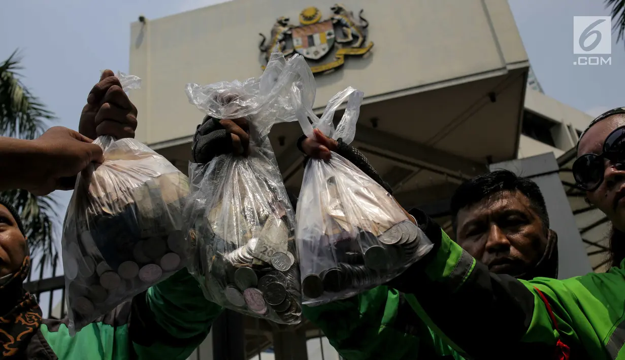 Pengemudi ojek online menunjukkan kantong plastik berisi uang saat berunjuk rasa di depan Kedubes Malaysia, Jakarta, Selasa (3/9/2019). Mereka memprotes penyataan kontroversial bos Big Blue Taxi, perusahaan taksi Malaysia, terkait rencana Gojek mengaspal di Negeri Jiran. (Liputan6.com/Faizal Fanani)