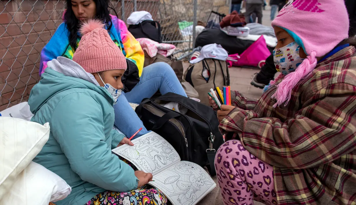 Dua imigran muda dari Venezuela berbagi buku mewarnai sambil menunggu bantuan di El Paso, Texas, Amerika Serikat, 18 Desember 2022. Kota-kota perbatasan Texas bersiap menghadapi lonjakan sebanyak 5.000 imigran baru setiap hari yang melintasi perbatasan AS-Meksiko karena pembatasan imigrasi era pandemi berakhir minggu ini. (AP Photo/Andres Leighton)