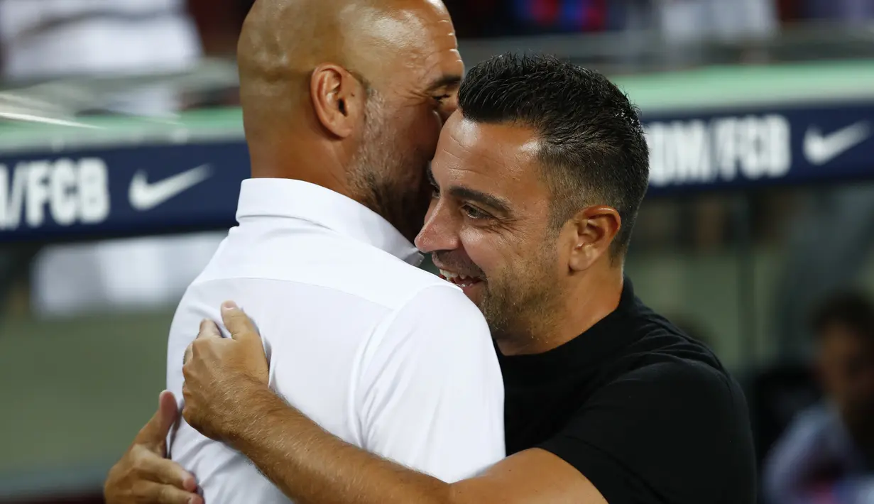 Pelatih Barcelona Xavi Hernandez memeluk manajer Manchester City, Pep Guardiola pada sebuah laga amal di Stadion Camp Nou, Kamis (25/8/2022) dinihari WIB. Pertandingan ini menjadi pertemuan perdana Pep Guardiola dan Xavi Hernandez yang pernah bekerja sama di Barcelona sebagai pelatih dan pemain selama rentang waktu 2008–2012. (AP Photo/Joan Monfort)