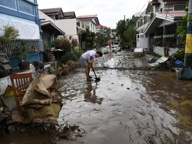 Seorang warga menyekop lumpur dari jalananan setelah banjir akibat Topan Goni di Kota Batangas, selatan Manila, Filipina, Senin (2/11/2020). Badan Bencana Negara mencatat sedikitnya 16 orang tewas akibat topan terkuat di dunia tahun ini, yang menghantam Filipina pada hari Minggu. (TED ALJIBE / AFP)