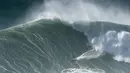 Seorang peselancar menunggangi ombak selama sesi selancar derek di Praia do Norte di Nazare, Portugal (29/10/2020). Gelombang besar, yang ditimbulkan oleh Badai Epsilon di Atlantik Utara, mencapai Portugis pantai barat menarik peselancar ombak besar ke Nazare. (AP Photo/Pedro Rocha)