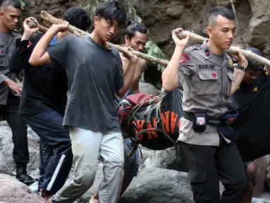 Petugas kepolisian dan warga saat mengevakuasi salah satu jenazah korban banjir bandang di kawasan Air Terjun Dua Warna, Sibolangit, Deli Serdang, Sumatera Utara, Senin (16/5). 17 jenazah korban dilaporkan telah ditemukan. (ALBERT DAMANIK / AFP)