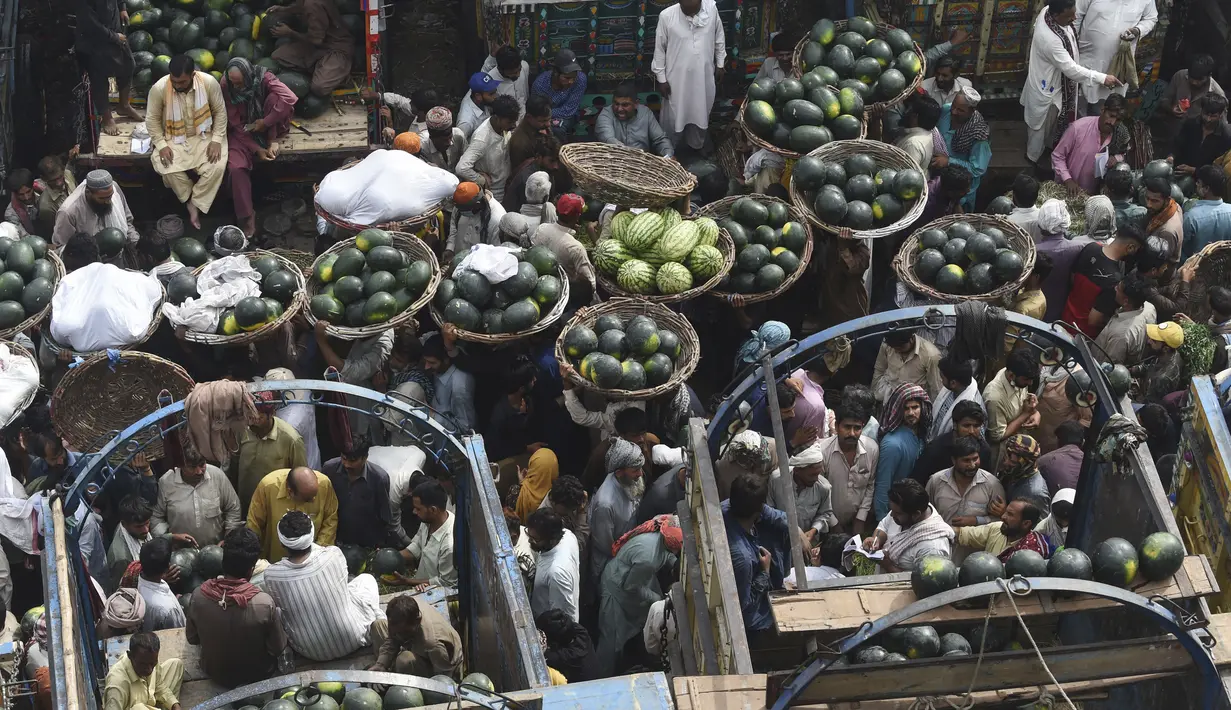 Orang-orang berdagang semangka di pasar buah di Lahore, Pakistan (12/4/2022).  Semangka biasa dipanen buahnya untuk dimakan segar atau dibuat jus. (AFP/Arif Ali)