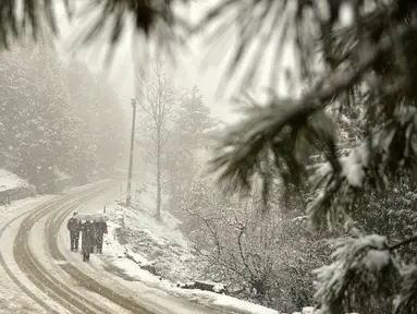Pejalan kaki melewati sepanjang jalan yang tertutup salju di Gulmarg, sekitar 55 km sebelah utara Srinagar, Kashmir, Selasa (3/1). Gelombang dingin yang melanda Kashmir kian parah hingga mencapai suhu di bawah nol derajat celcius. (Tauseef Mustafa/AFP)
