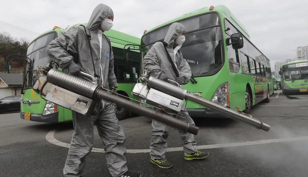 Pekerja mengenakan pakaian pelindung saat menyemprotkan Disinfektan sebagai tindakan pencegahan virus corona COVID-19 di tempat parkir bus di Seoul, Korea Selatan, Rabu, (26/2/2020). Jumlah infeksi corona di Korea Selatan melonjak lagi pada Rabu (26/2). (AP Photo/Ahn Young-joon)
