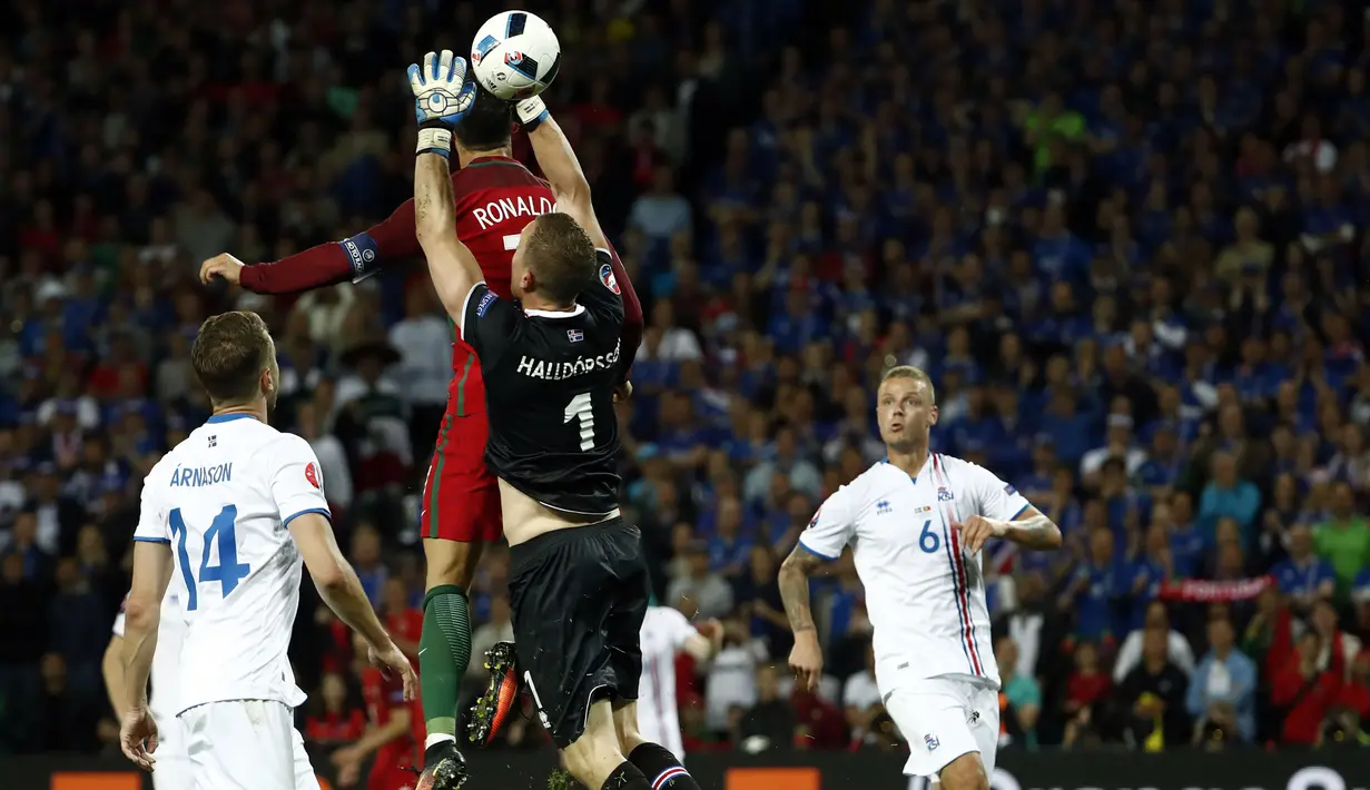 Kiper Islandia, Hannes Halldersson, menepis sundulan bintang Portugal, Cristiano Ronaldo, pada laga Grup F Piala Eropa di Stadion Geoffroy Guichard, St Etienne, Rabu (14/6/2016). Islandia bermain imbang 1-1 dengan Portugal. (AFP/Odd Andersen)