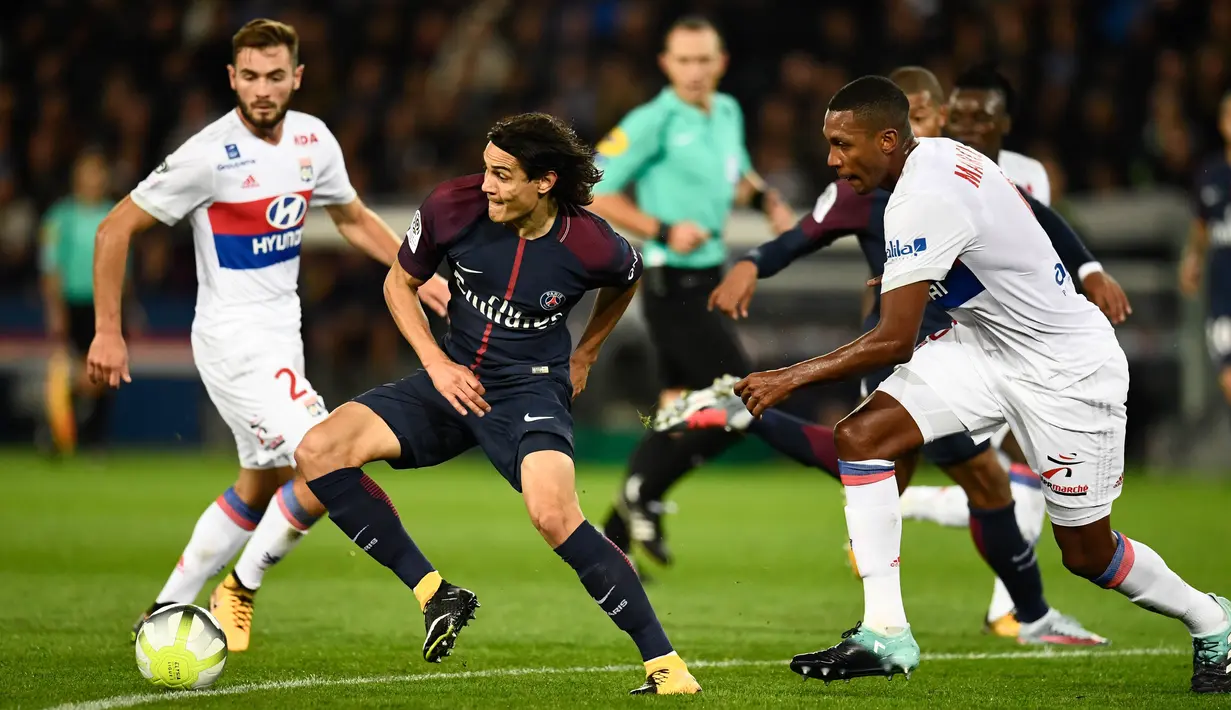 Aksi pemain PSG, Edinson Cavani melewati adangan pemain Lyon pada lanjutan Ligue 1 Prancis di Parc des Princes stadium, Paris, (17/9/2017). PSG menang 2-0. (AFP/Christhope Simon)