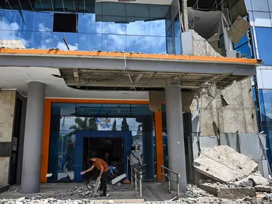 Pekerja membersihkan puing-puing dari sebuah gedung bank yang rusak akibat gempa berkekuatan magnitudo 7,7 di Ruteng, Manggarai, Nusa Tenggara Timur, Minggu, 16 Agustus 2026. (AFP/ Juni Kriswanto)